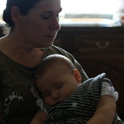 Un joli bébé assoupi dans les bras de sa grand-mère